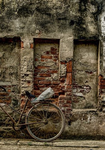 photo of bike against old wall on sidewalk